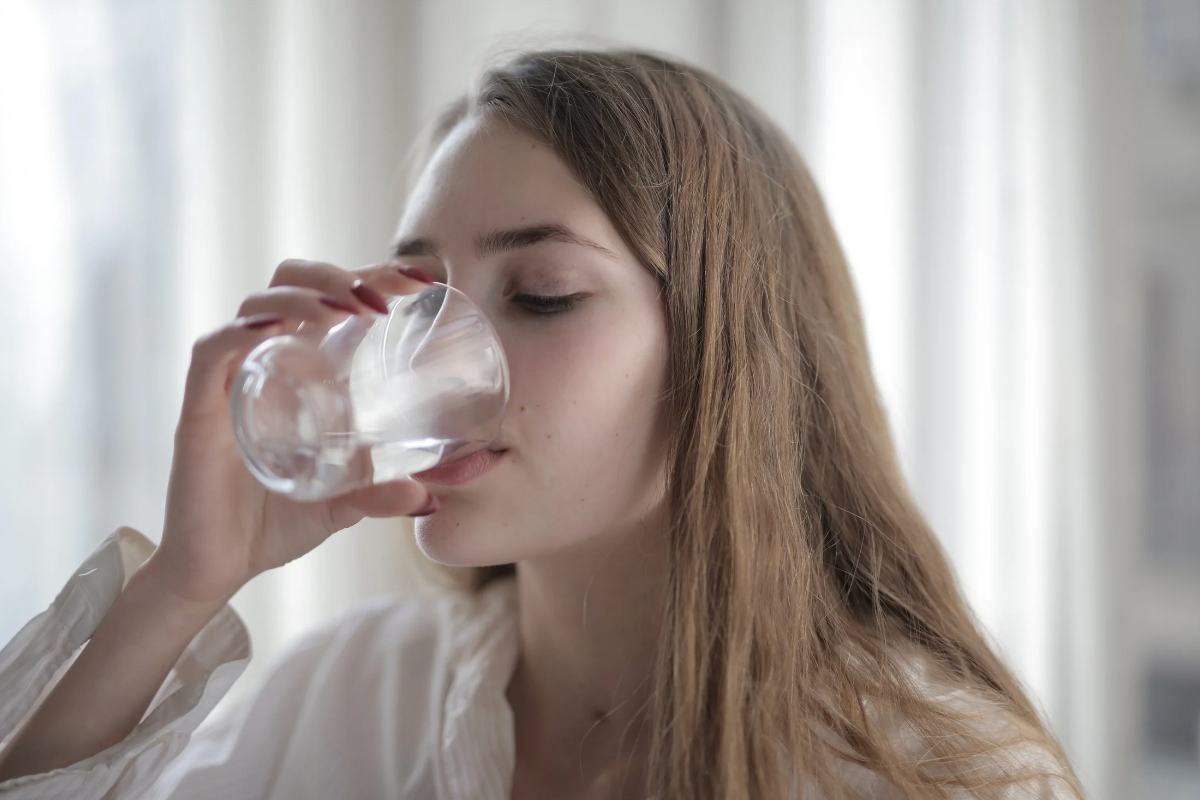 donna che sorseggia un bicchiere d'acqua